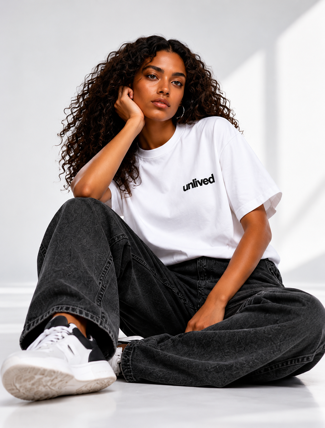 Femme portant le t-shirt blanc UNLIVED dans un studio minimaliste